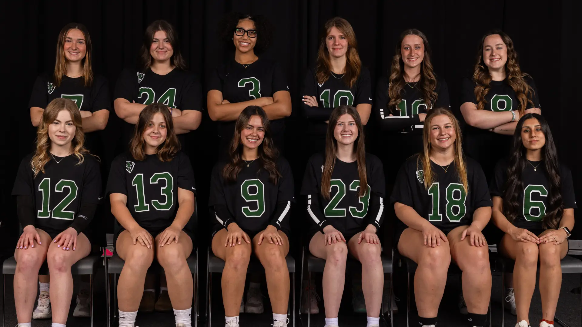 Twelve members of the Women's Volleyball Club pose together in two rows, wearing numbered black jerseys with green trim.