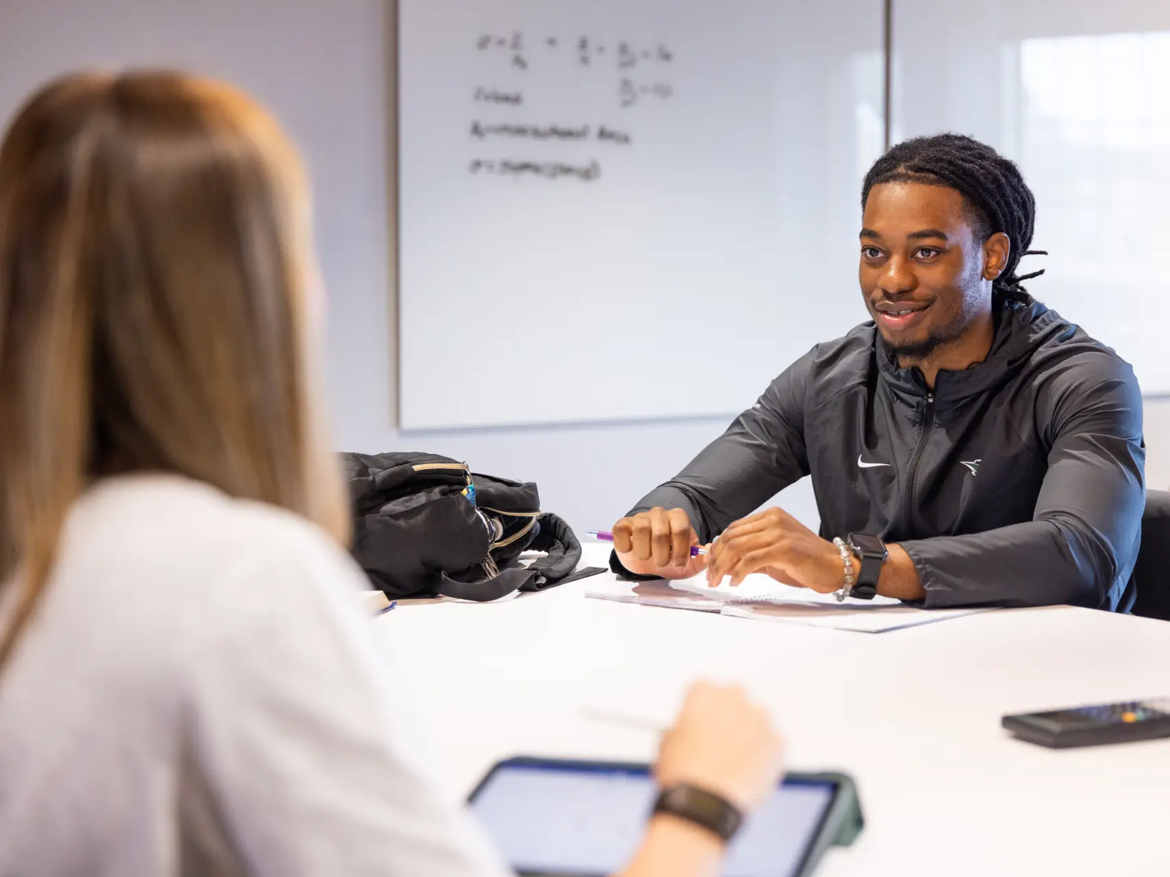 Two students discussing homework at table in the study lounge.