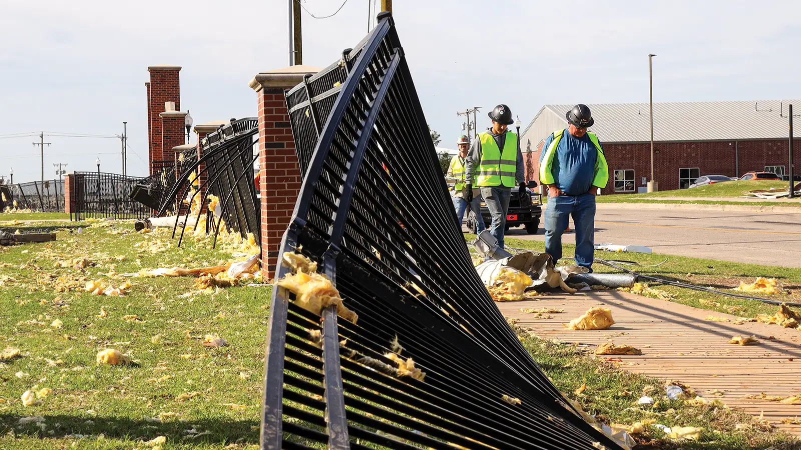Workers survey fence damage after the April 19, 2023 tornado on the OBU campus