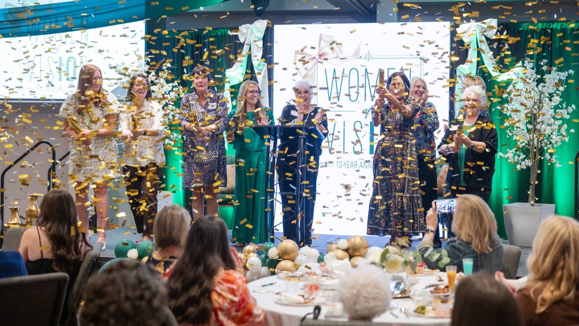 Women on stage firing confetti cannons.
